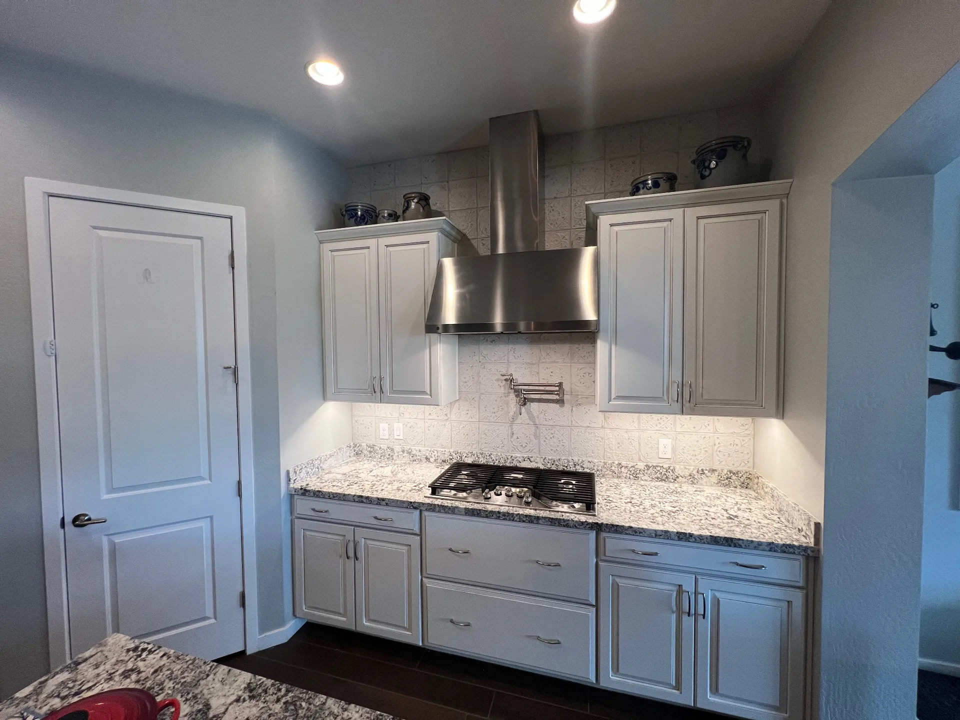 Kitchen after backsplash installation with under-cabinet lighting and pot filler