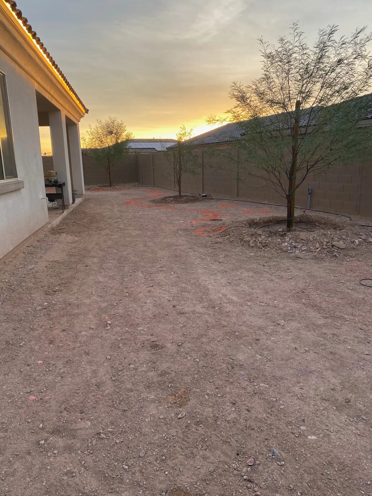 Backyard before - bare dirt lot at sunset