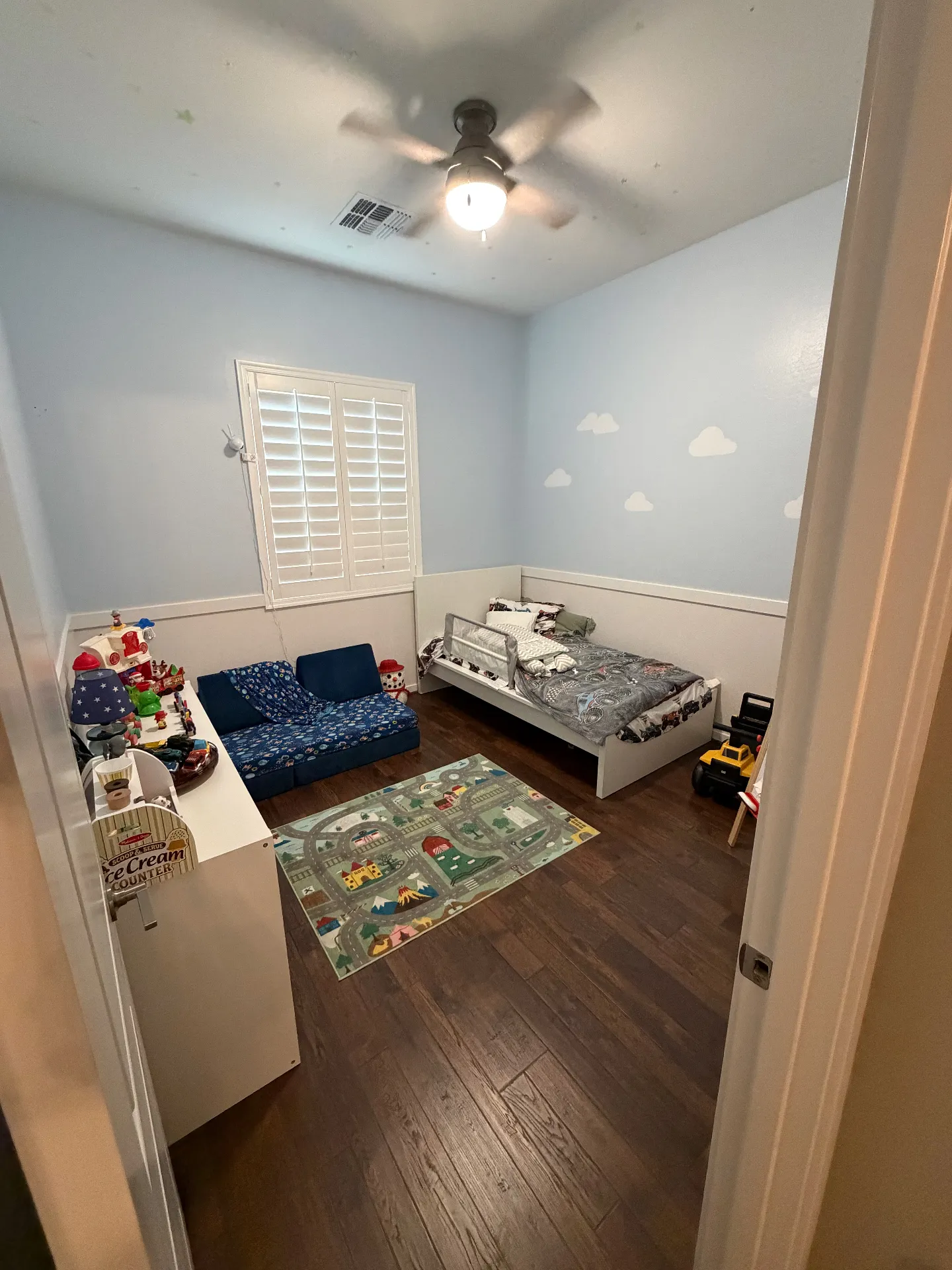 Kids room after renovation - wood flooring, wainscoting, and ceiling fan
